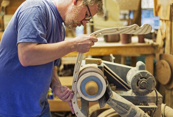 Carpenter polishing wood with sander