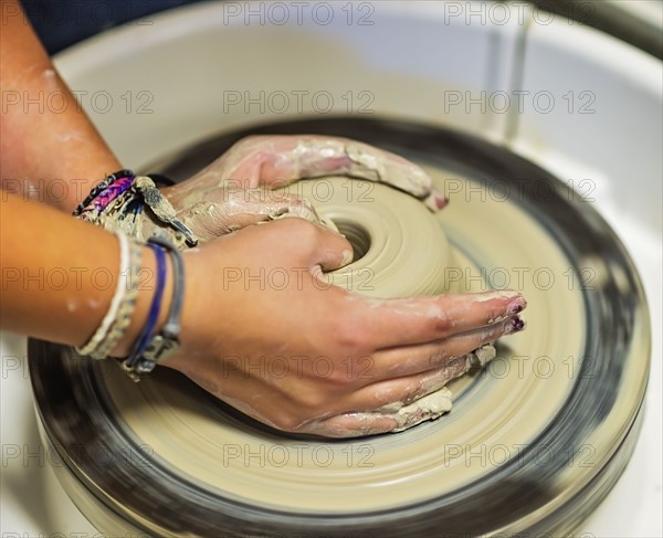 Woman shaping clay bowl on pottery wheel