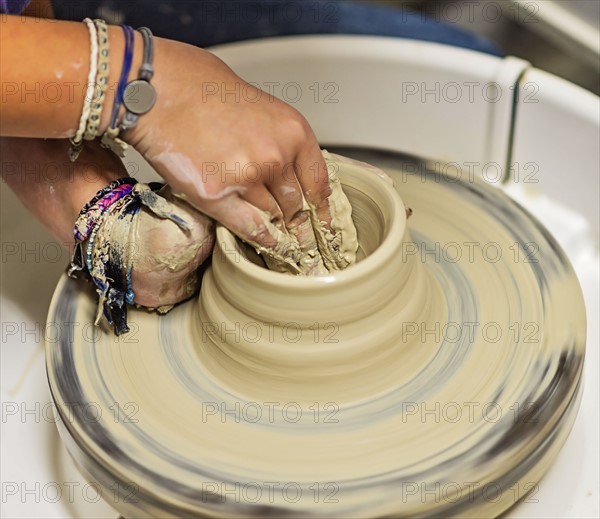 Woman shaping clay bowl on pottery wheel