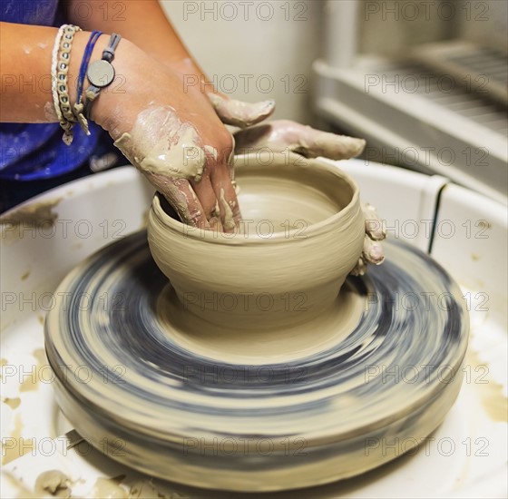 Woman shaping clay bowl on pottery wheel