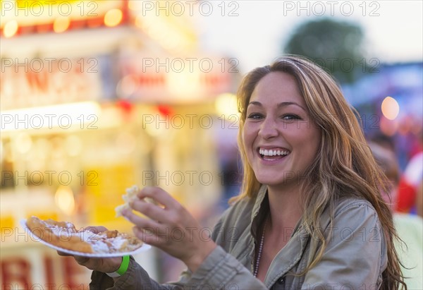 Woman eating funnel cake at funfair