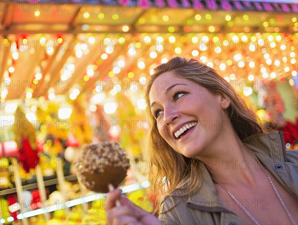 Woman holding caramel apple at funfair