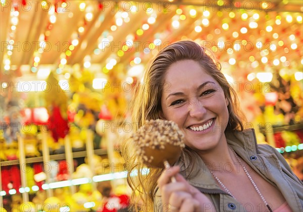 Woman holding caramel apple at funfair