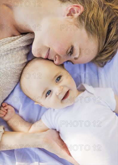 Mother lying down with baby boy (6-11 months)