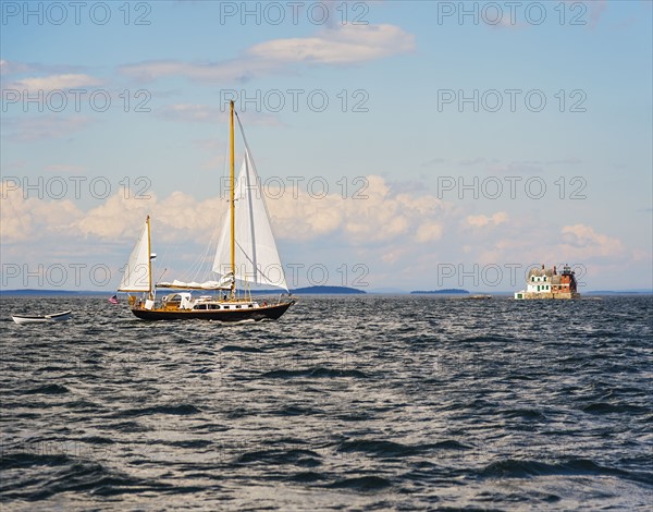 Sailboat in sea and Rockland Harbor Breakwater Lighthouse in distance