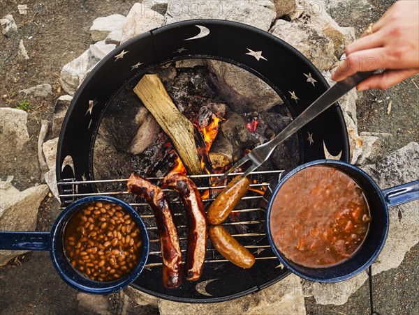 Man's hand cooking dinner on camp fire