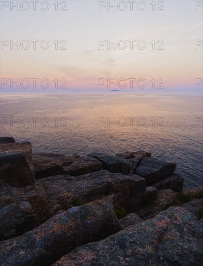 Rocky cliff by sea at sunrise