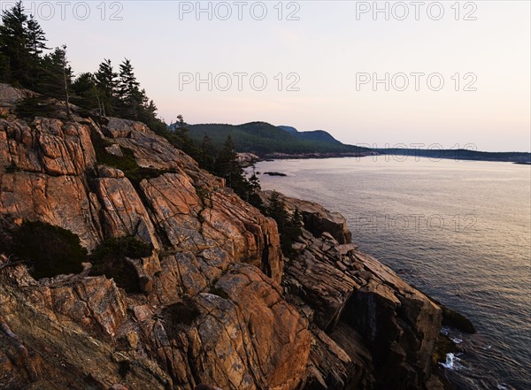 Rocky cliff by sea at sunrise