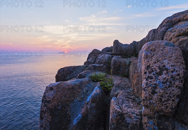 Rocky cliff by sea at sunrise