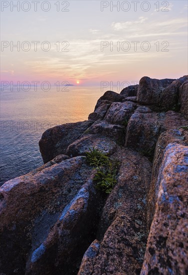 Rocky cliff by sea at sunrise