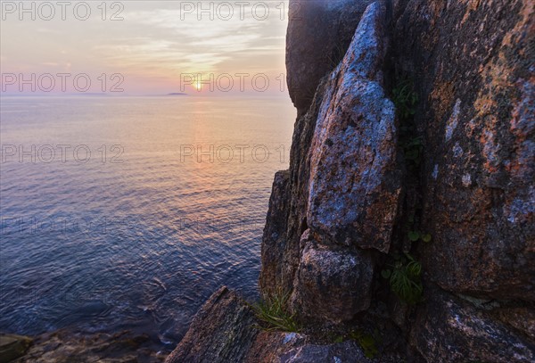 Rocky cliff by sea at sunrise