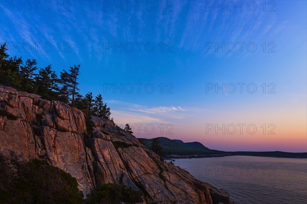 Rocky cliff by sea at sunrise