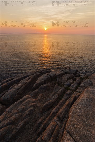 Rocky cliff by sea at sunrise