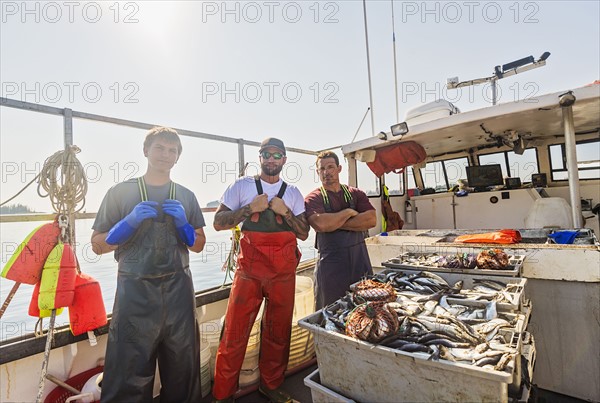 Portrait of three fishermen standing on boat