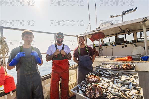 Portrait of three fishermen standing on boat