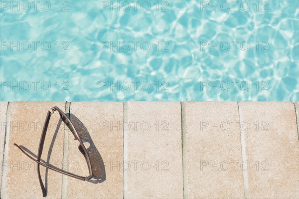 Sunglasses on brick ledge by pool