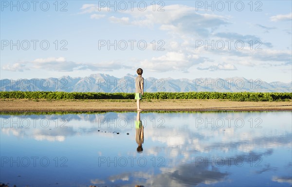 Boy (6-7) standing at water's edge