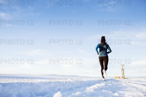 Rear view of mature woman running in snow