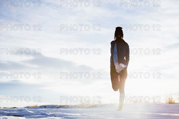 Mature woman stretching in snow