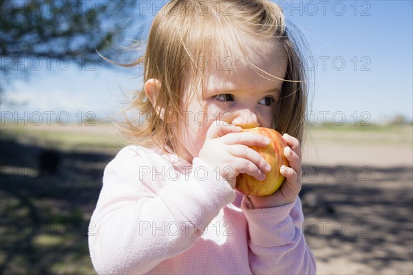 Portrait of girl (2-3) eating apple