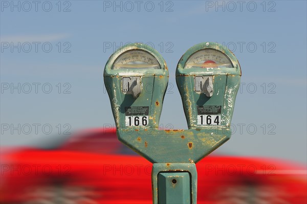 Old parking meter against panning red car