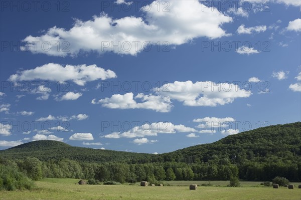 Landscape with field, hay bales and hills