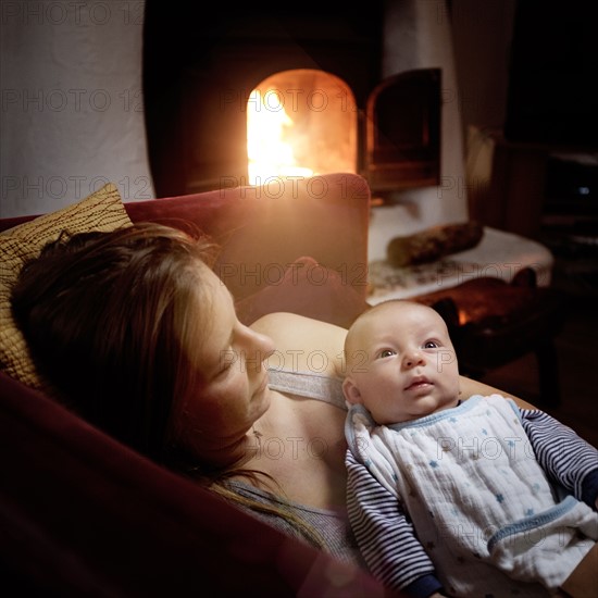 Woodstock, Woman resting with baby girl (2-5 months) on sofa.