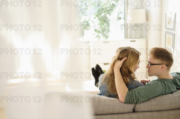 Young couple sitting face to face on sofa.