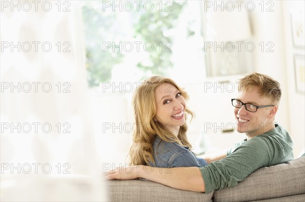 Portrait of young couple sitting on sofa.