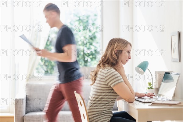 Side-view of young couple working at home.