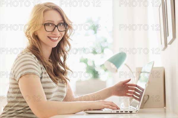 Portrait of young woman working on laptop at home.