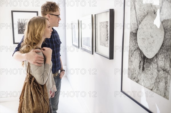 Young couple looking at photographs at museum.