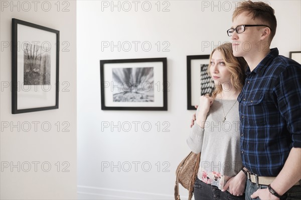 Young couple looking at photographs at museum.