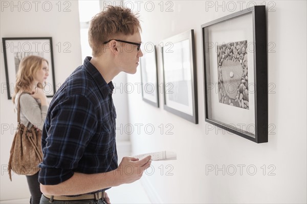 Young couple looking at photographs at museum.