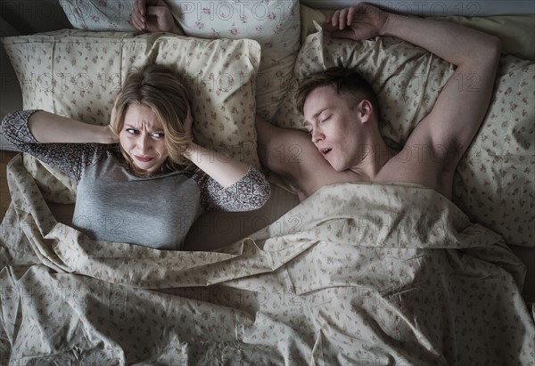 Young couple in bed, man snoring.