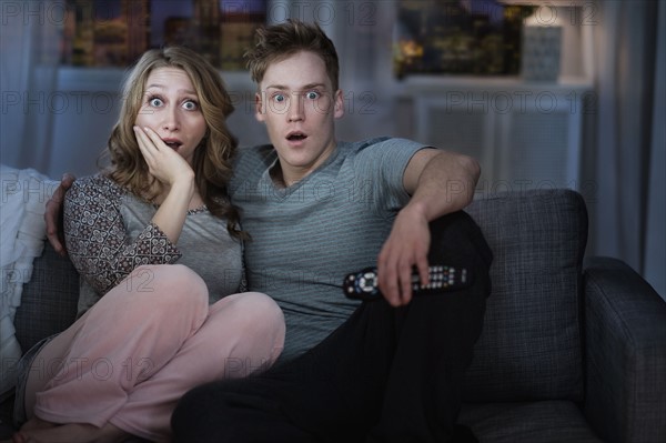 Young couple watching TV at night.