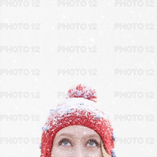 Woman in red knit hat looking up.