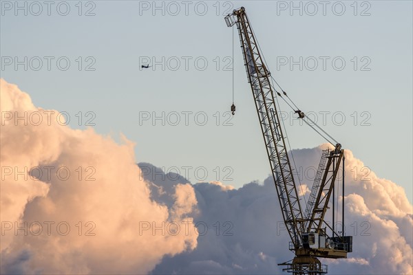 Crane with airplane in background at sunset.