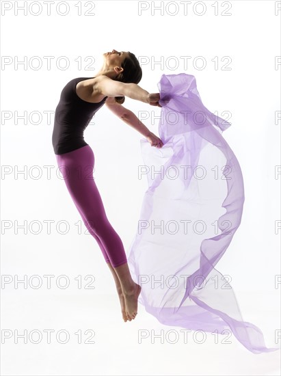 Woman with sheer fabric jumping.