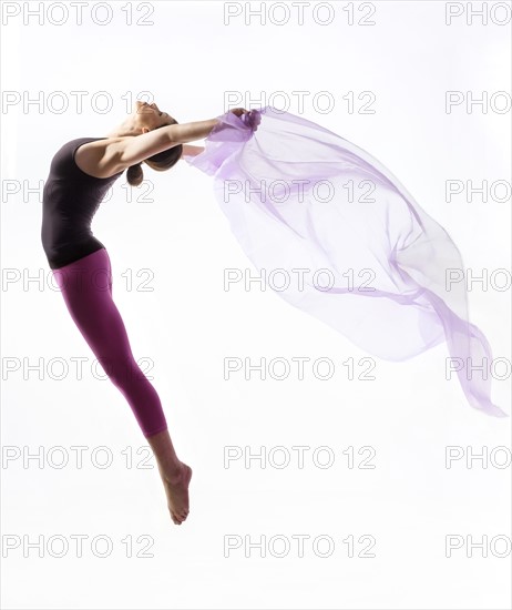 Woman with sheer fabric jumping.