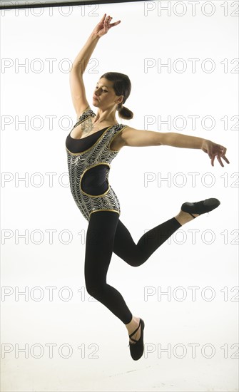 Young woman jumping on black background.