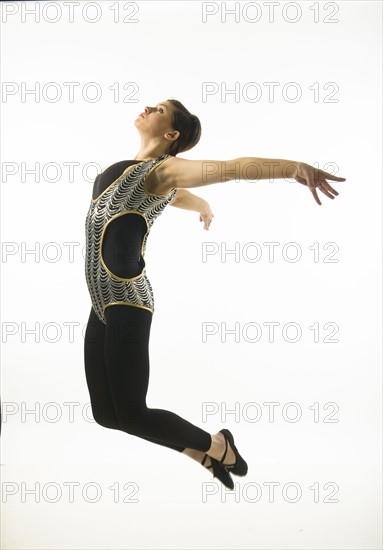 Young woman dancing against white background.