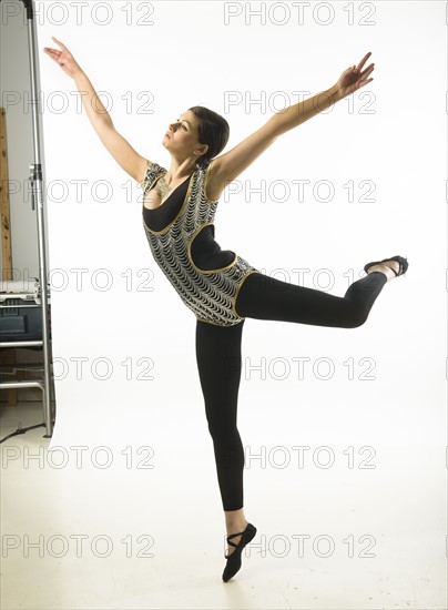 Young woman dancing against white background.