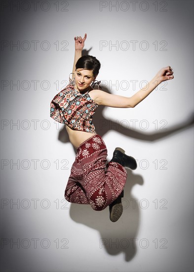 Young woman jumping against white background.