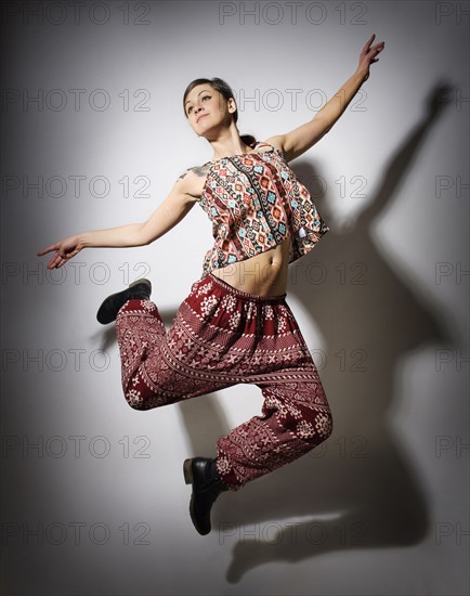 Young woman jumping against white background.