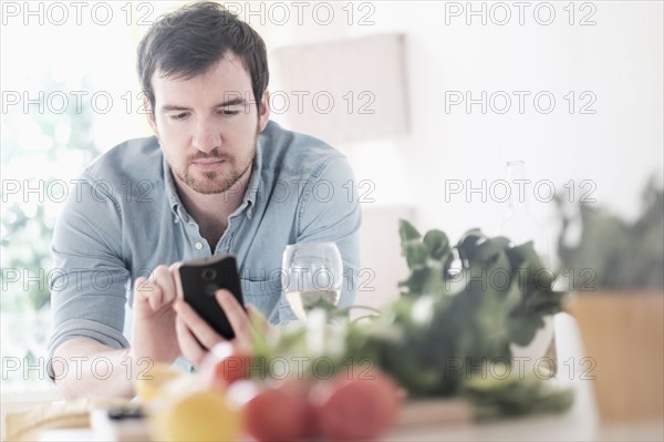 Man using phone in kitchen.