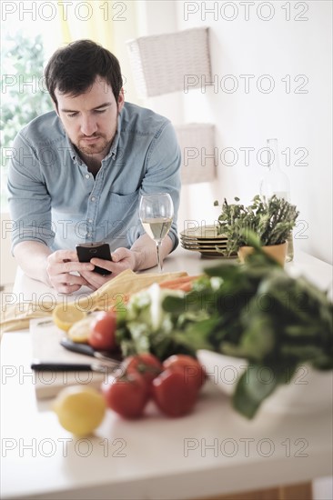 Man using phone in kitchen.