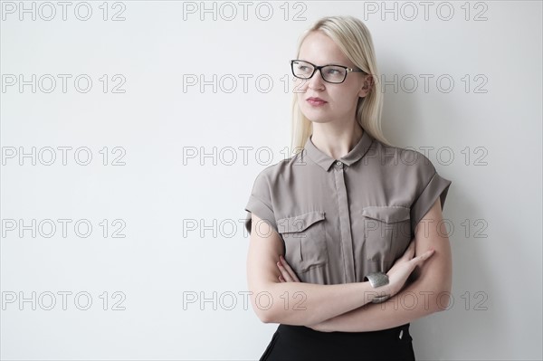 Young woman standing against white wall.