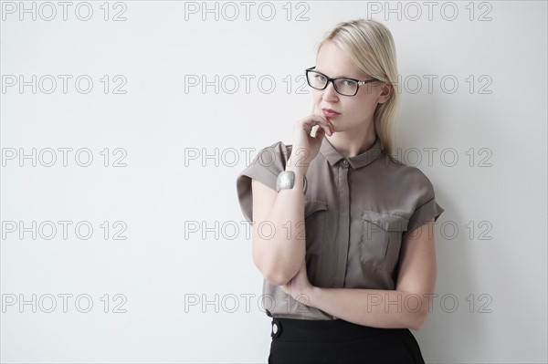 Young woman standing against white wall.