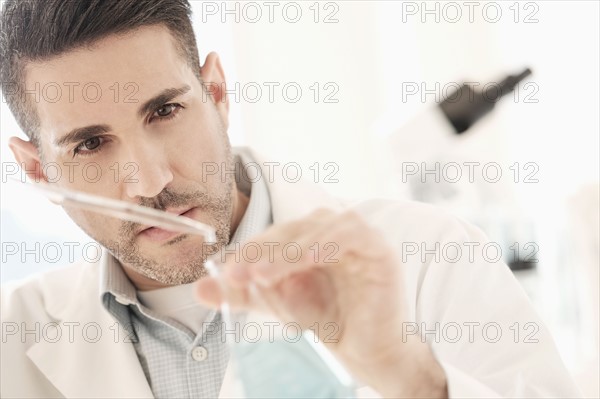 Man pouring liquid into conical flask.